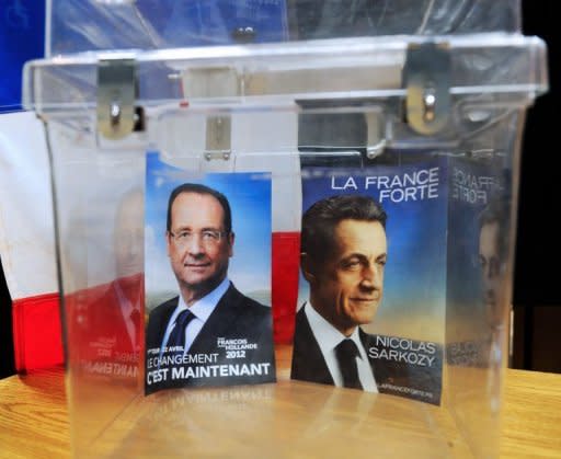 Declarations of faith from French 2012 presidential candidates, France's President and Union for a Popular Movement (UMP) candidate Nicolas Sarkozy (R) and France's Socialist Party (PS) candidate Francois Hollande, are put in an urn in front of a voting booth in Bethune, northern France