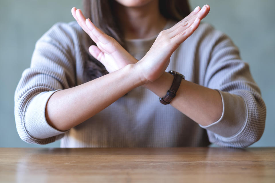 Closeup image of a woman making crossed arms sign