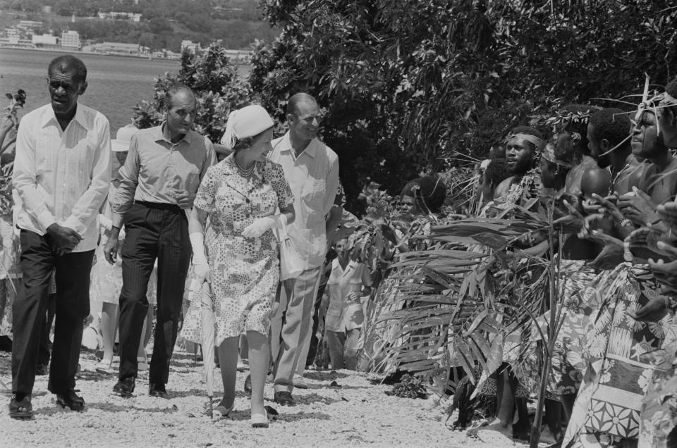 Men in traditional dress line the road during a visit by Queen Elizabeth (centre) and Prince Philip (centre, right) to Port Vila, Vanuatu, off the north-east coast of Australia, February 1974. (Photo by McCabe/Daily Express/Hulton Archive/Getty Images)