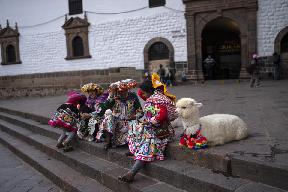 Women from the town of Paucartambo wait for tourists to take a photo with them in exchange for money, in downtown Cusco, Peru, Wednesday, Feb. 1, 2023. (AP Photo/Rodrigo Abd)
