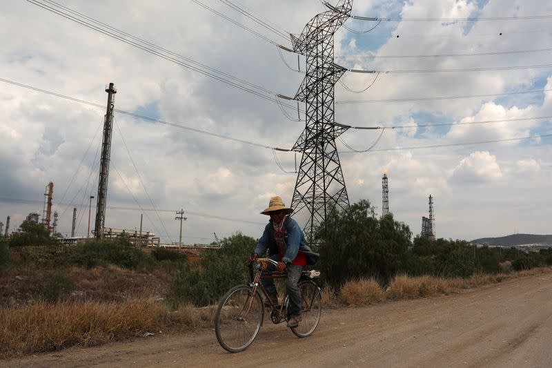 A man rides a bike on a road near high-voltage transmission lines near the Tula power plant owned by state-owned power company Commission Federal de Electricidad, or CFE, in Tula de Allende