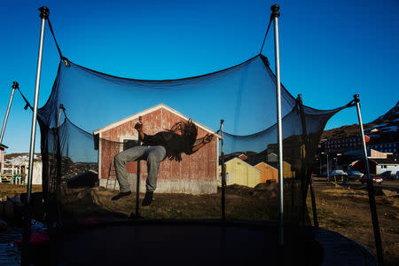 A young girl plays on a trampoline in the evening sunshine in the town of Tasiilaq, Greenland, June 18, 2018. REUTERS/Lucas Jackson