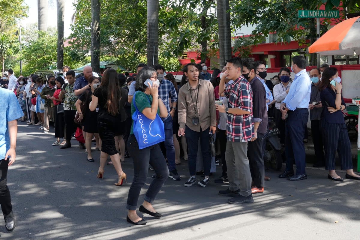 People wait outside an office building after being evacuated following an earthquake at the main business district in Jakarta (AP)