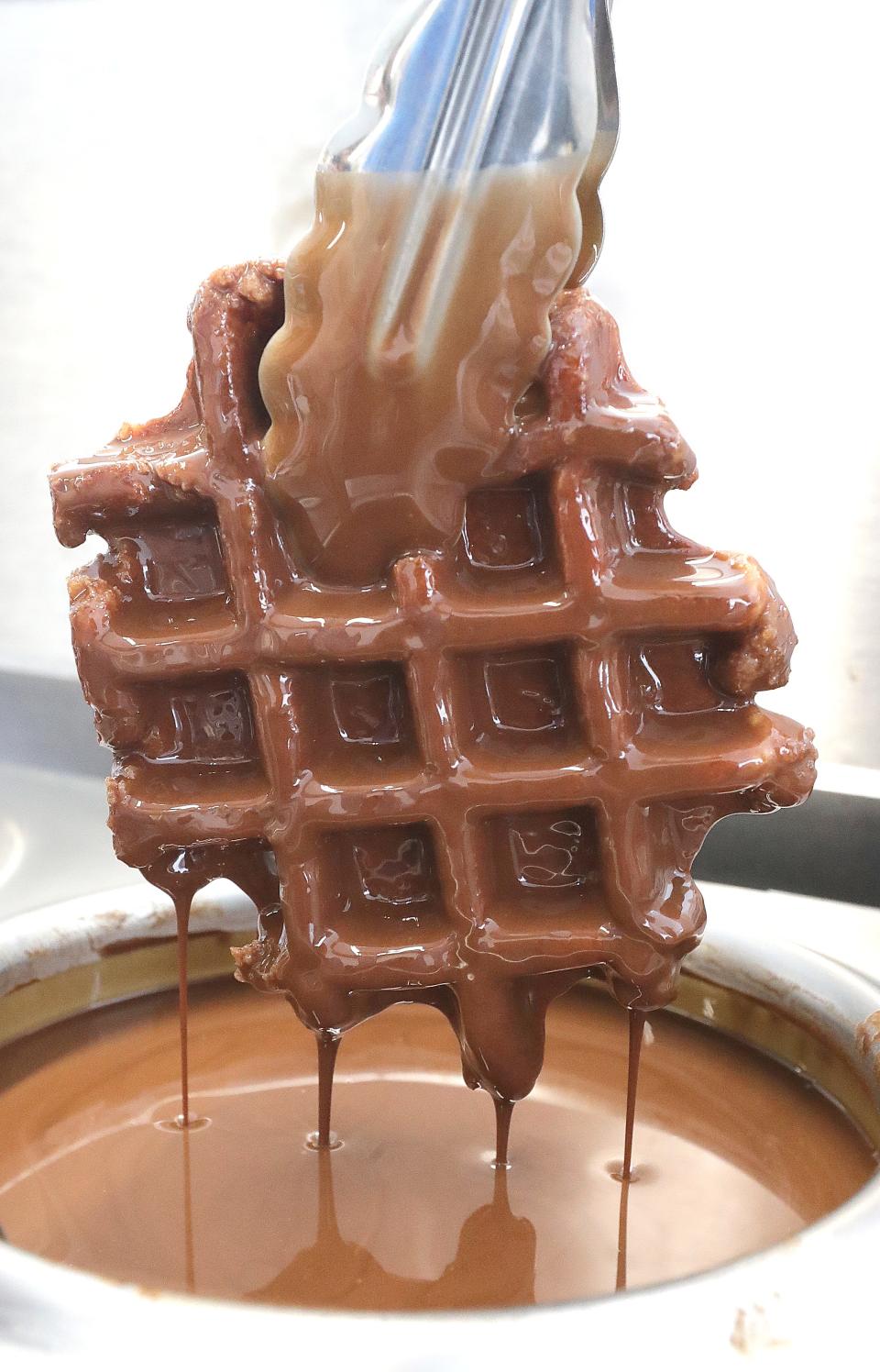 Biggins' Big Dip employee Payton Anzaldi dips a waffle in chocolate while building a solar eclipse sundae.