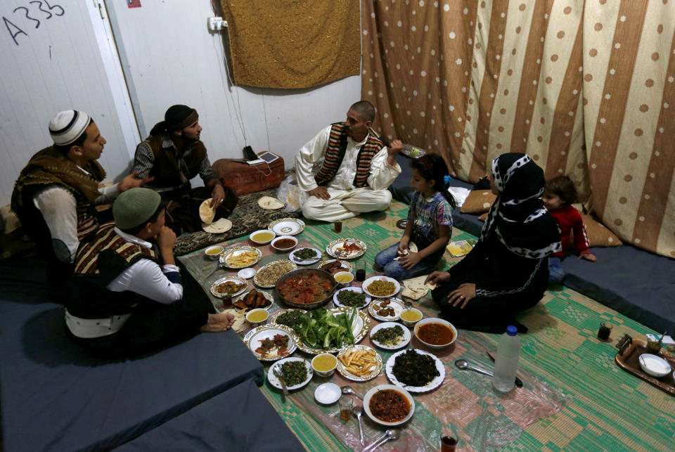 Abu Rustom, founder of a Syrian refugee folklore troupe eats Iftar food with his family and troupe members at the Al-Zaatari refugee camp June 1.