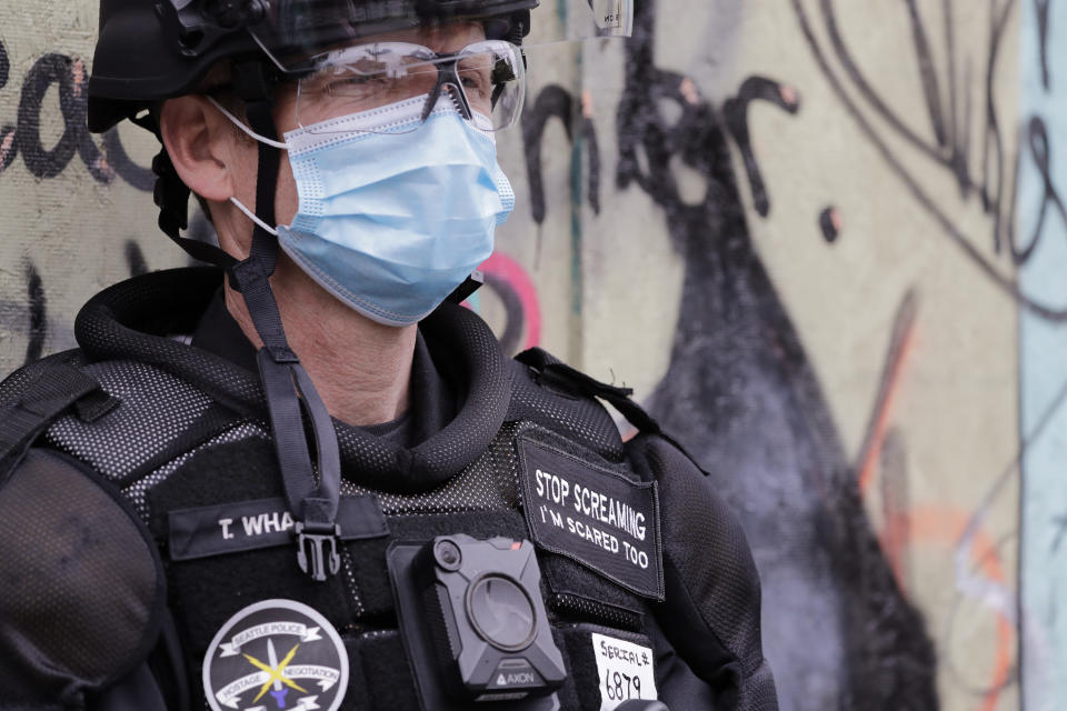 Seattle police officer Terry Whalen, a member of the department's hostage negotiating team, wears a patch reading "Stop screaming, I'm scared too" while standing with other officers blocking an intersection Wednesday, July 1, 2020, in Seattle, where streets had been blocked off in an area demonstrators had occupied for weeks. Whalen says that the patch, a gift to him, helps calm interactions with people who may be upset. Seattle police showed up in force earlier in the day at the "occupied" protest zone, tore down demonstrators' tents and used bicycles to herd the protesters after the mayor ordered the area cleared following two fatal shootings in less than two weeks. The "Capitol Hill Occupied Protest" zone was set up near downtown following the death of George Floyd while in police custody in Minneapolis. (AP Photo/Elaine Thompson)