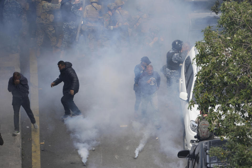 Retired army soldiers and other protesters who are demanding better pay, run from the tear gas after they clashed with Lebanese army and riot police, in Beirut, Lebanon, Wednesday, March 22, 2023. Lebanese security forces fired tear gas to disperse hundreds of protesters who tried to break through the fence leading to the government headquarters in downtown Beirut Wednesday amid widespread anger over the harsh economic conditions in the country. (AP Photo/Hussein Malla)