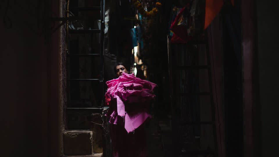 A woman carrying fabric walks along a narrow alley in Dharavi on April 14. - Noemi Cassanelli/CNN