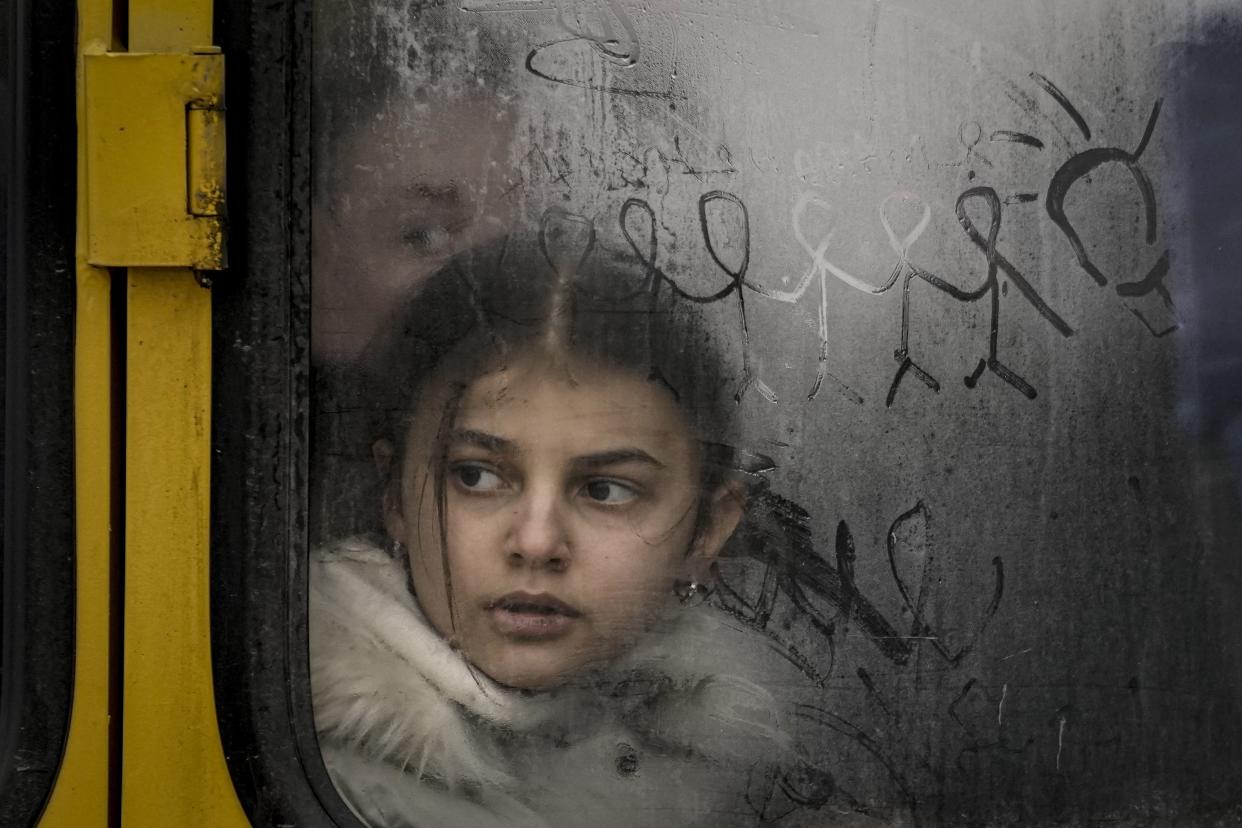 FILE - A child looks out a steamy bus window with drawings on it as civilians are evacuated from Irpin, on the outskirts of Kyiv, Ukraine, on March 9, 2022. 