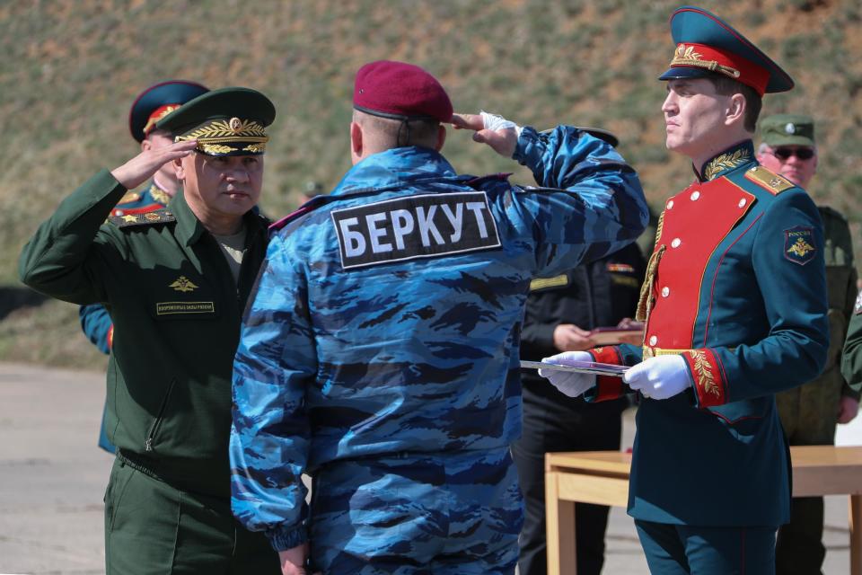 In this photo provided by the Russian Defense Ministry, Russian Defense Minister Sergei Shoigu, left, awards a former Ukrainian special forces "Berkut" officer, back to camera, at a military base in Sevastopol, Crimea, Monday, March 24, 2014. Shoigu's visit comes as Ukraine's fledgling government on Monday ordered Ukrainian troops to withdraw from Crimea, ending days of wavering as Russian troops consolidate control over the peninsula. (AP Photo/Press Service of Russian Defense Ministry, Vadim Savitsky, Pool)