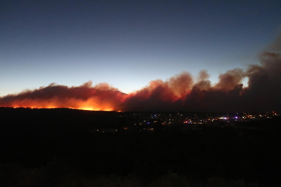 A wildfire burning on the outskirts of Flagstaff, Ariz., casts a glow above neighborhoods on Sunday, June 12, 2022. Evacuations have been ordered for homes in the area. (AP Photo/Felicia Fonseca)