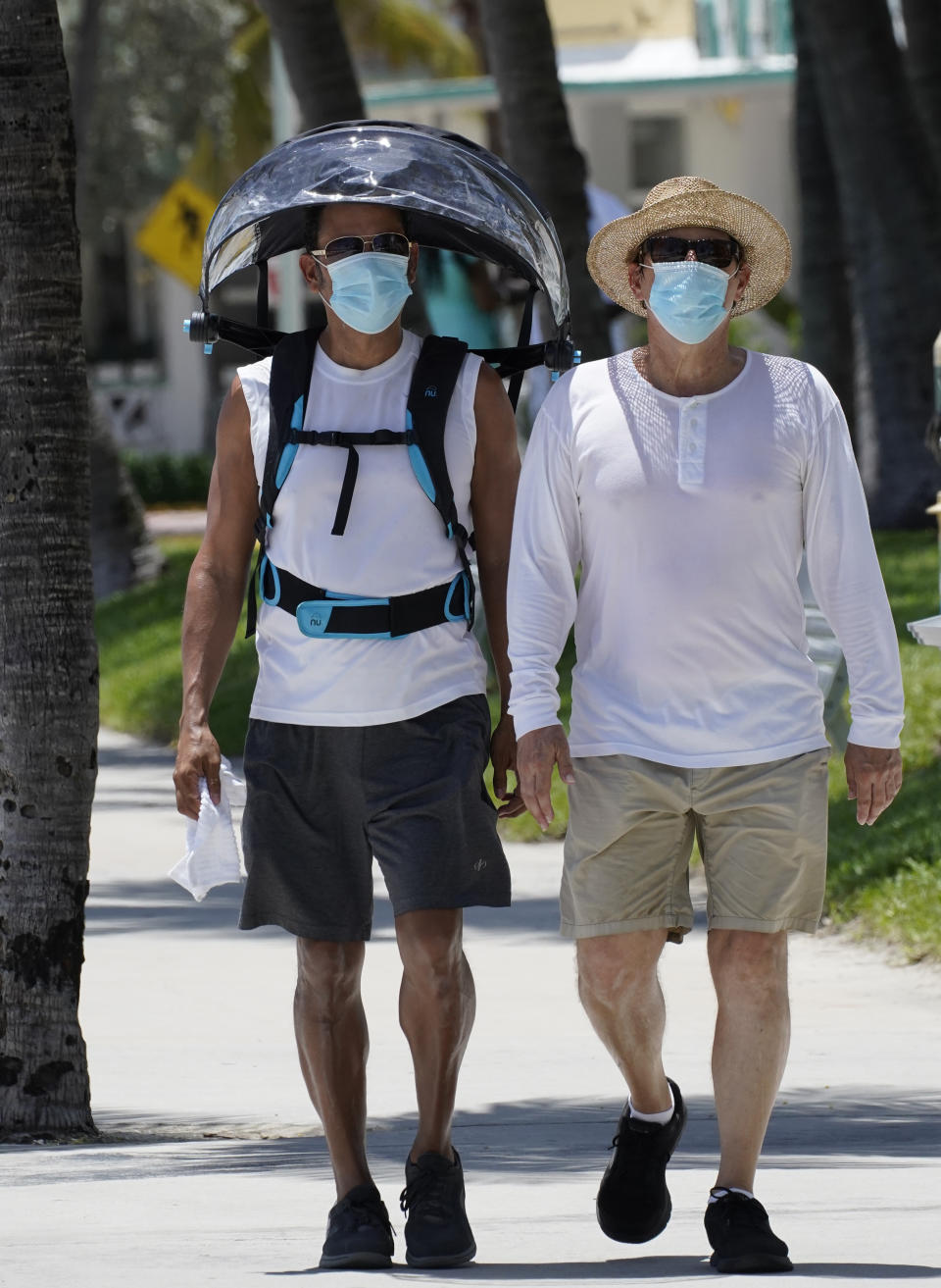 A pair of beach goers wear masks to prevent the spread of the new coronavirus, Tuesday, Aug. 11, 2020, on Miami Beach, Florida's famed South Beach. Florida added 276 fatalities to its coronavirus death toll on Tuesday, a new state record. (AP Photo/Wilfredo Lee)