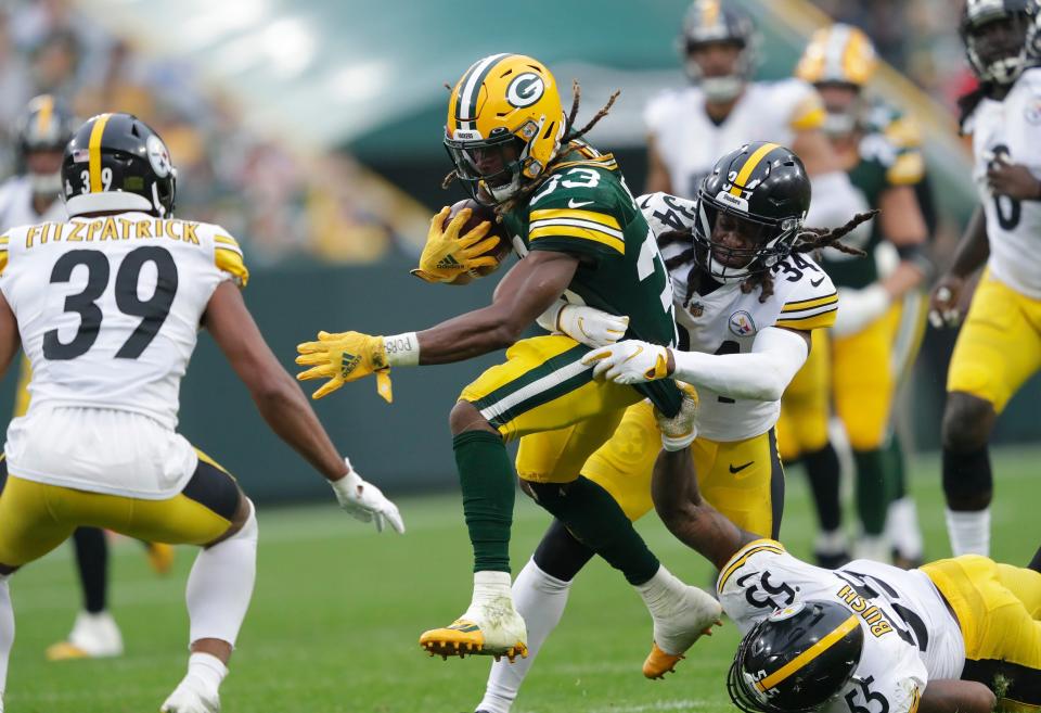 Green Bay Packers running back Aaron Jones (33) gets a first down on a reception against Pittsburgh Steelers safety Terrell Edmunds (34) linebacker Devin Bush (55) and safety Minkah Fitzpatrick (39) during their football game Sunday, Oct. 3, 2021, at Lambeau Field.