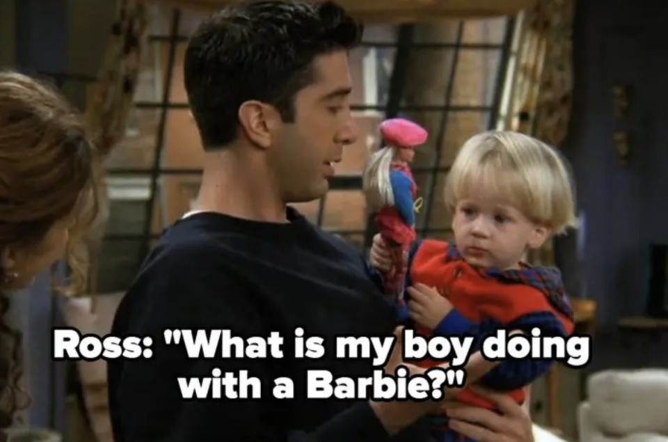 Ross holding his toddler son and saying "What is my boy doing with a Barbie?"