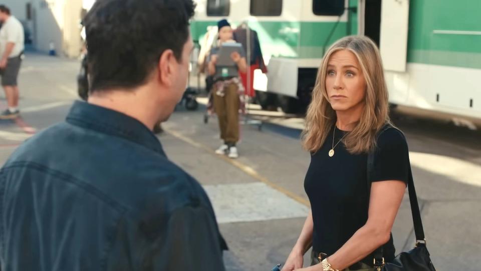 Jennifer Aniston looks surprised speaking to a man on a movie backlot in an Uber Eats commercial with David Schwimmer