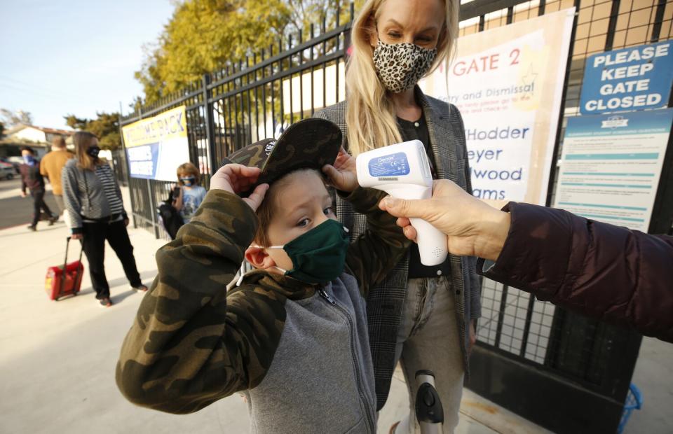 Feb. 2: First-grader Baron White holds his baseball hat up to have his temperature taken outside school