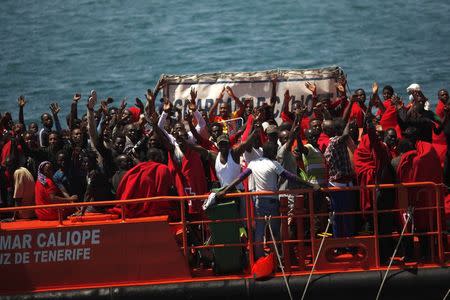 African immigrants wave to fishermen (not pictured) as they arrive on a rescue ship at the southern Spanish port of Tarifa, near Cadiz, southern Spain August 12, 2014. REUTERS/Jon Nazca