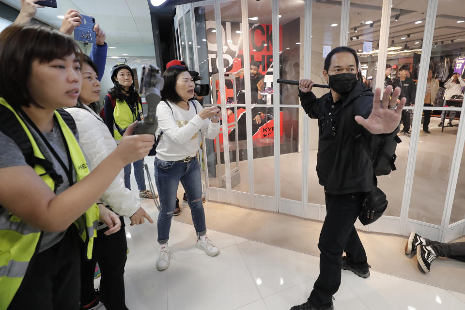 An undercover policeman holds a baton during a demonstration at a shopping mall popular with traders from mainland China near the Chinese border in Hong Kong, Saturday, Dec. 28, 2019. Protesters shouting "Liberate Hong Kong!" marched through a shopping mall Saturday to demand that mainland Chinese traders leave the territory in a fresh weekend of anti-government tension. (AP Photo/Lee Jin-man)