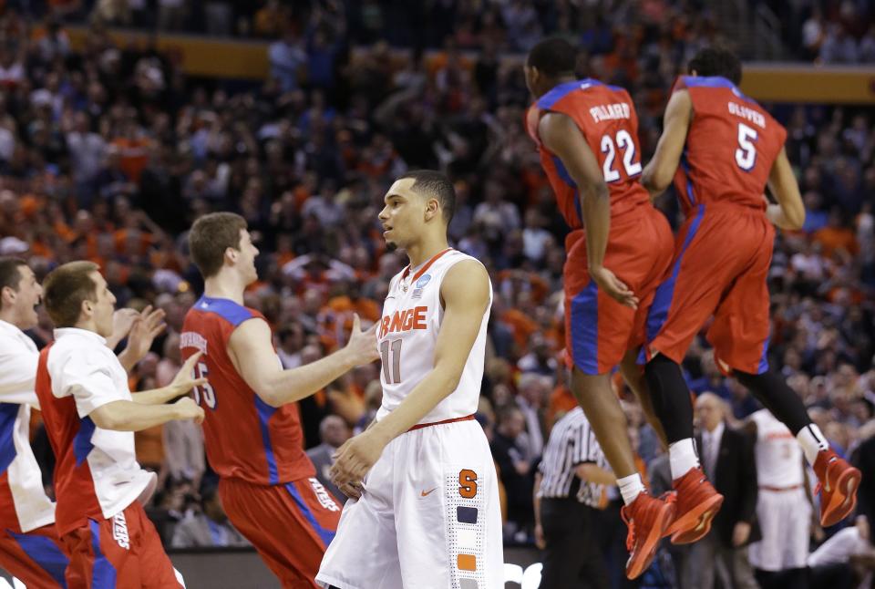 Syracuse's Tyler Ennis (11) reacts as Dayton's Kendall Pollard (22) and Devin Oliver (5) celebrate with teammates during the second half of a third-round game in the NCAA men's college basketball tournament in Buffalo, N.Y., Saturday, March 22, 2014. Dayton won 55-53. (AP Photo/Frank Franklin II)
