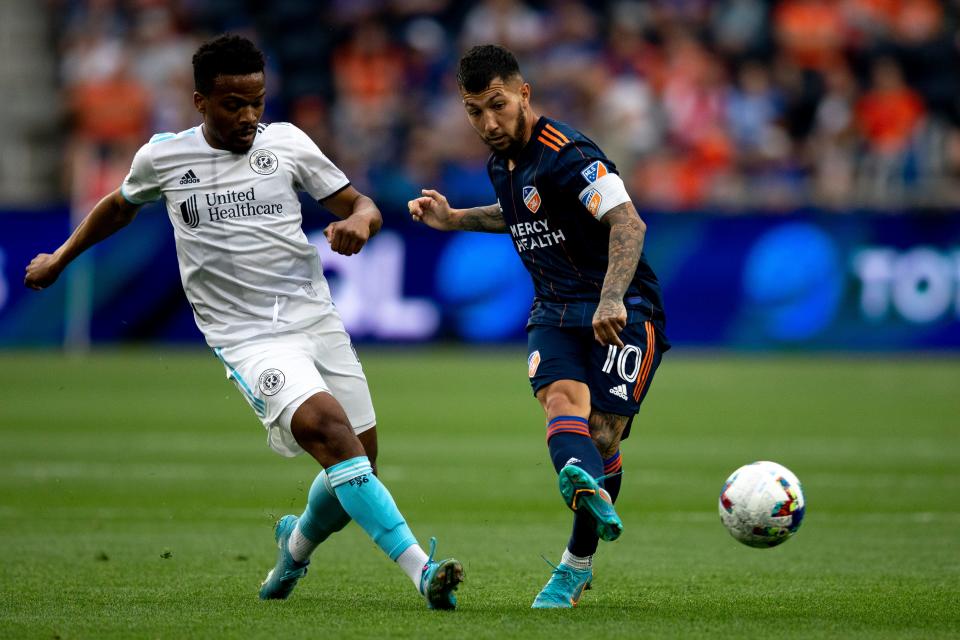 FC Cincinnati midfielder Luciano Acosta (10) passes as New England Revolution midfielder Wilfrid Kaptoum (5) defends in the first half of the MLS match between FC Cincinnati and New England Revolution at TQL Stadium in Cincinnati on Saturday, May 21, 2022. 