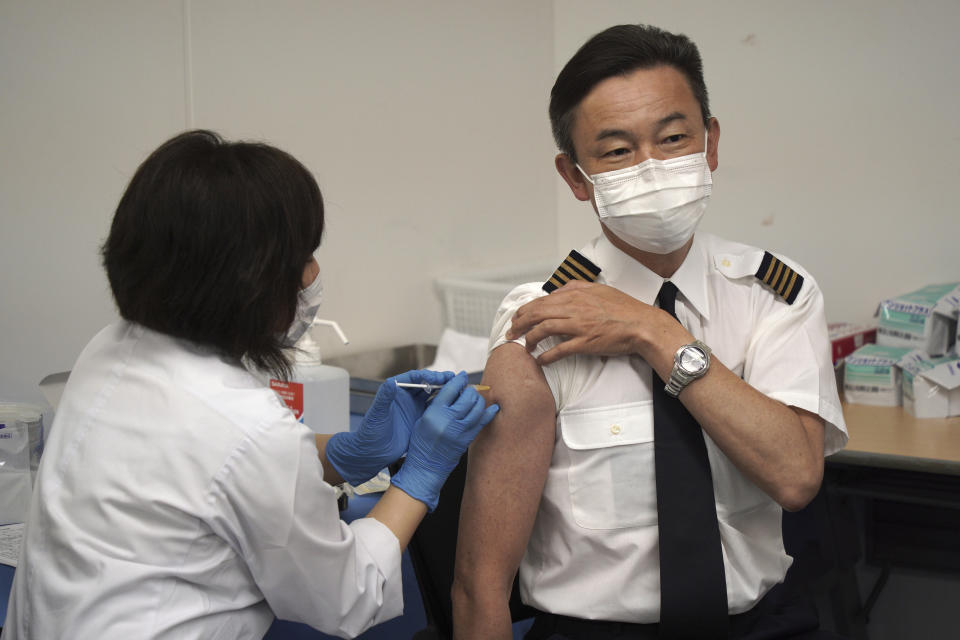 Satoru Shimizu, a 56-year-old All Nippon Airlines pilot, takes Moderna's COVID-19 vaccine shot in Haneda Airport as the airline company began its workplace vaccination in Tokyo, on Sunday, June 13, 2021. (AP Photo/Kantaro Komiya)