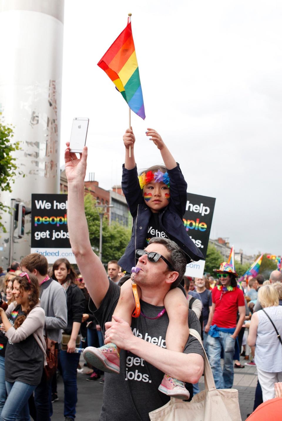 A man with a girl on his shoulders walking through the street at a Dublin Gay Pride parade in June 2015.