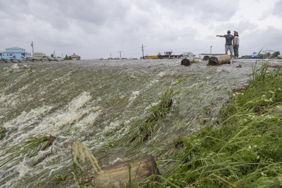 Chris Nguyen and his father, Trung, look at the moving water that breached the top of a levee in Plaquemines Parish just south of New Orleans as Hurricane Barry makes landfall along the coast on Saturday, July 13, 2019. (Chris Granger/The Advocate via AP)