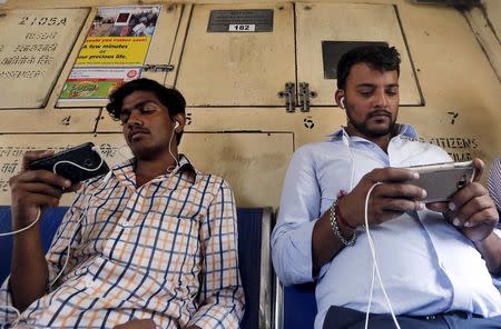 Commuters watch videos on their mobile phones as they travel in a suburban train in Mumbai, India, April 2, 2016. REUTERS/Shailesh Andrade/Files