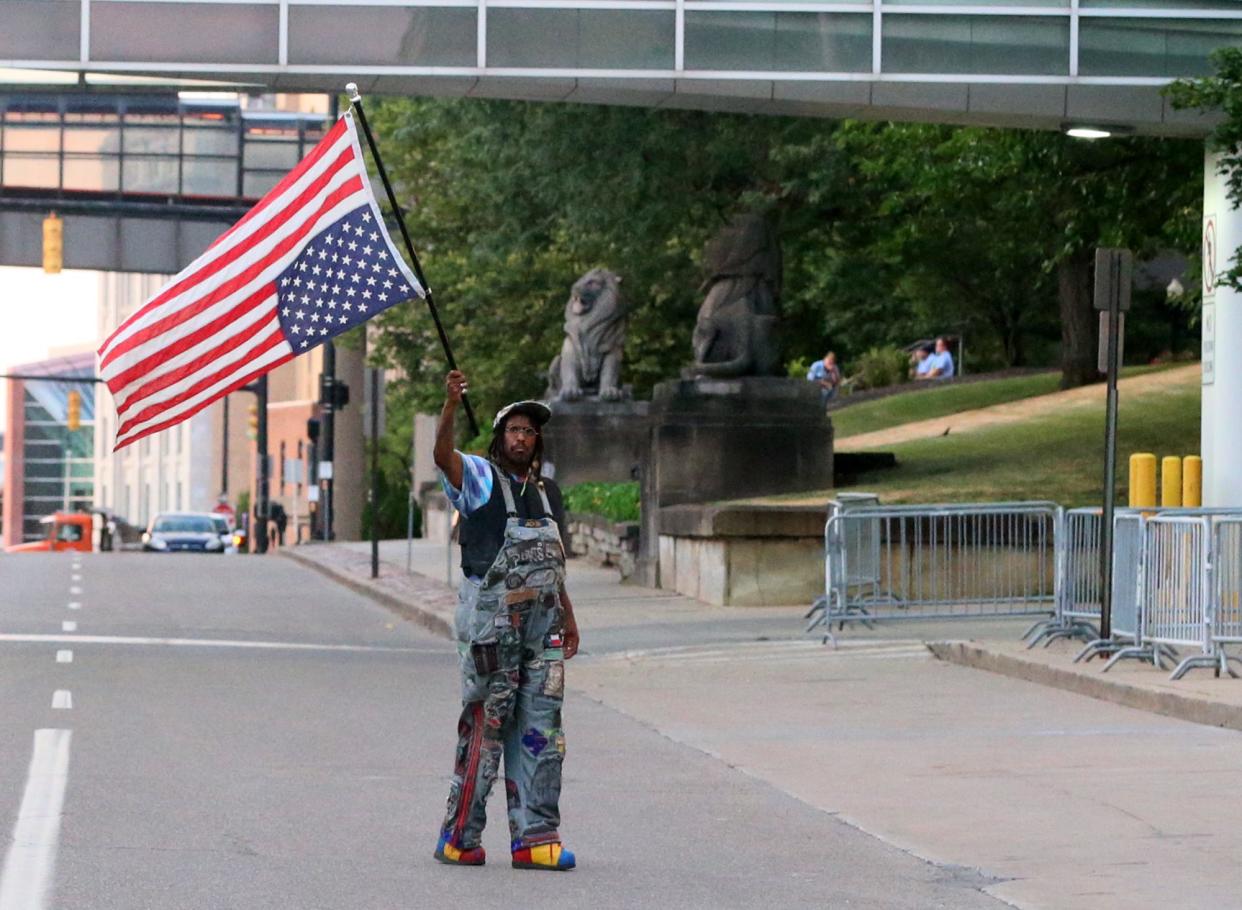 A man waves an upside down American flag Thursday evening in front of the Harold K. Stubbs Justice Center in Akron protest of the police shooting death of Jayland Walker.