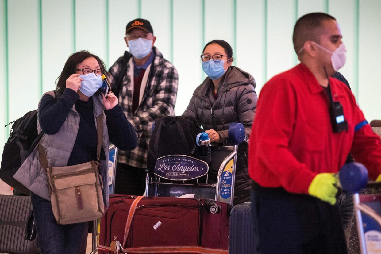 Passengers wear face masks to protect against the spread of the Coronavirus as they arrive on a flight from Asia at Los Angeles International Airport: AFP via Getty Images