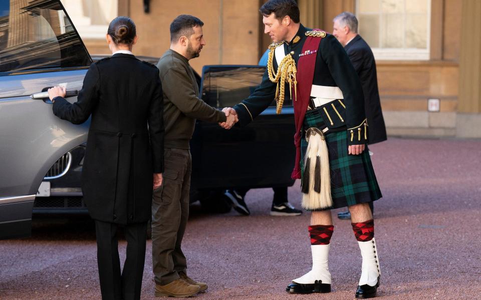 Ukraine's President Volodymyr Zelensky (2L) is greeted by Lieutenant Colonel Johnny Thompson, equerry to King Charles III, as he arrives for an audience with the King at Buckingham Palace, London on February 8, 2023