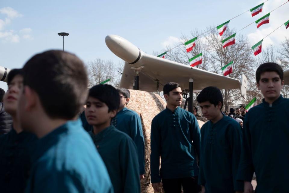 Iranian youth stand under an Iranian-made unmanned aerial vehicle (UAV), the Shahed-136, during a rally to mark the 44th anniversary of the Victory of Iran's 1979 Islamic Revolution in Tehran, Iran on Feb. 11, 2023. (Morteza Nikoubazl/NurPhoto via Getty Images)