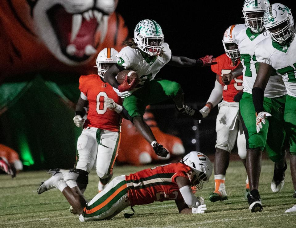 Frank Starks of Fort Myers leaps over a Dunbar defender in the 3S regional quarterfinals on Friday, Nov. 10, 2023, at Dunbar High School in Fort Myers.