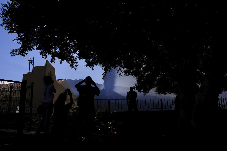 People look towards a volcano as it continues to erupt in El Paso on the canary island of La Palma, Spain, Saturday Oct. 9, 2021. A new lava flow has belched out from the La Palma volcano and it threatens to spread more destruction on the Atlantic Ocean island where molten rock streams have already engulfed over 1,000 buildings. The partial collapse of the volcanic cone overnight sent a new lava stream Saturday heading toward the western shore of the island. (AP Photo/Daniel Roca)