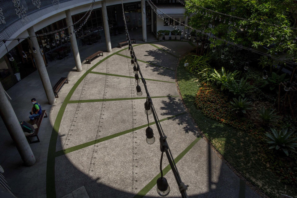 A food deliveryman sits at a courtyard of an empty mall in Bangkok, Thailand, Tuesday, March 24, 2020. Most popular shopping malls remained shut in Bangkok, except supermarkets and pharmacies to combat the spread of new coronavirus. Restaurant are allowed to operate only for takeout and delivery orders. For most people, the new coronavirus causes only mild or moderate symptoms. For some, especially older adults it can cause more severe illness. (AP Photo/Gemunu Amarasinghe)