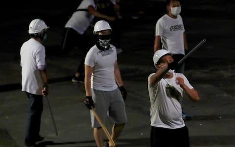 Men in white T-shirts with poles are seen in Yuen Long after they attacked pro-democracy activists at a train station, in Hong Kong - Credit: Reuters&nbsp;