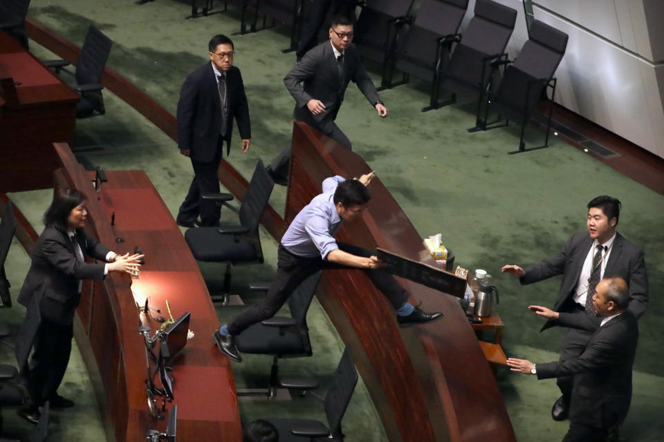 Security officers pursue pro-democracy lawmaker Au Nok-hin, center, as he leaps across desks to chase Hong Kong Chief Executive Carrie Lam as Lam leaves a question and answer session with lawmakers at the Legislative Council in Hong Kong, Thursday, Oct. 17, 2019. (AP Photo/Mark Schiefelbein)