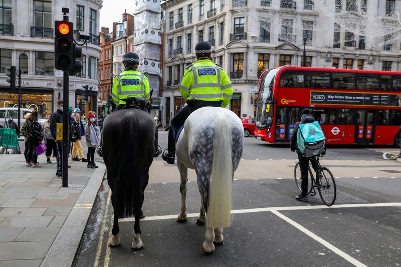 FILE PHOTO: Mounted police and a Deliveroo rider wait at a red light at Regent Street in London