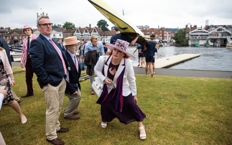 Spectators duck under a boat as a crew carry it to the water at the Henley - Credit: Jack Taylor/Getty Image