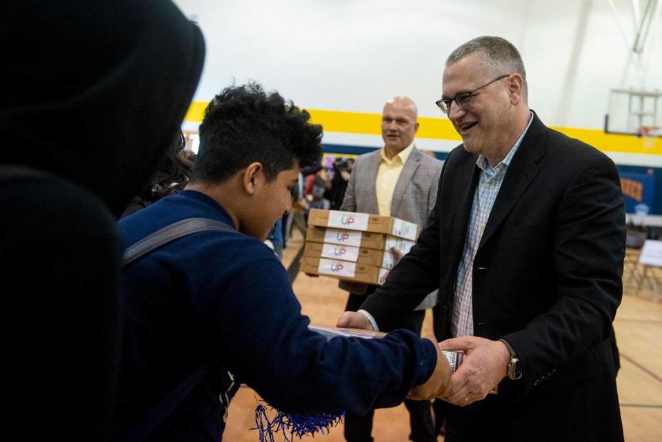 Comcast Chief Network Officer Elad Nafshi, right, hands out computers to eighth-graders during a ceremony announcing a $4.5 million investment to bring high-speed internet and broadband services to the area, at Cesar E. Chavez Middle School in Planada, Calif., on Monday, April 17, 2023. According to Nathan Ahle, Comcast Director of Government Affairs for the South Valley, the $4.5 million investment involves extending the existing network from nearby Merced into the town of Planada.