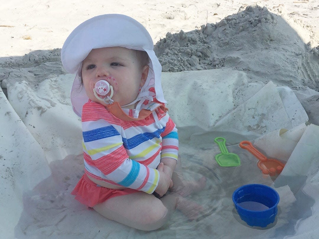 A baby playing in a DIY wading pool at the beach.