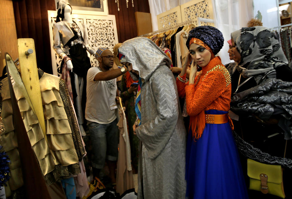 In this Thursday, May 30, 2013 photo, Indonesian Muslim women try on dresses during Islamic Fashion Fair in Jakarta, Indonesia. Indonesia is the world's most populous Muslim country, but most people follow a moderate form of the religion. Many women wear bright and creative headscarves along with brand-name jeans and long-sleeved fitted shirts. (AP Photo/Dita Alangkara)