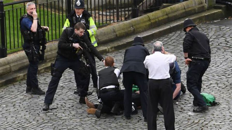 Police officers point a rifle at a man laying on the ground. Source: AP