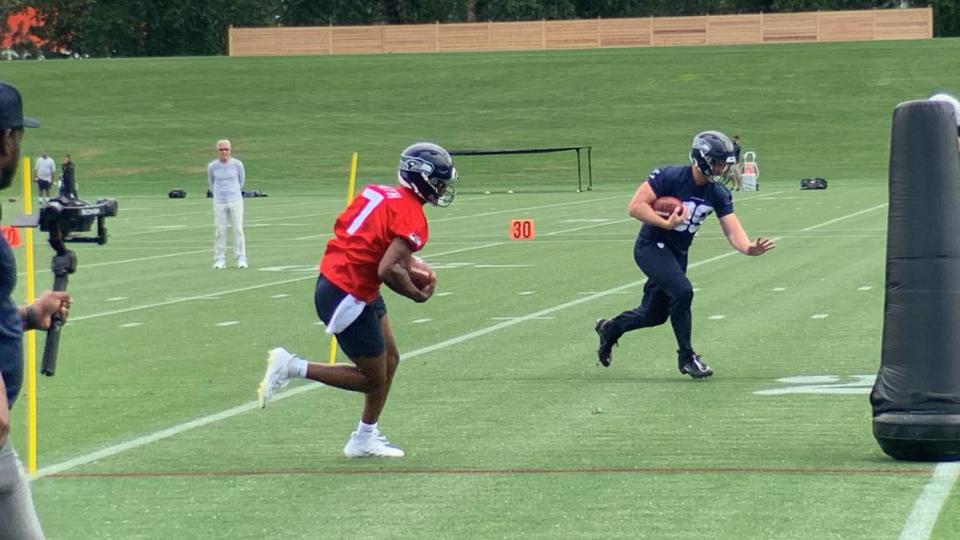 With coach Pete Carroll watching in the background, quarterback Geno Smith (7) and tight end Will Dissly (89, right) run through a drill offensive coordinator Shane Waldron led on chantge of direction and ball security through poles and pads. This was at the first of nine Seahawks OTA practices May 22, 2023, at team headquarters in Renton.