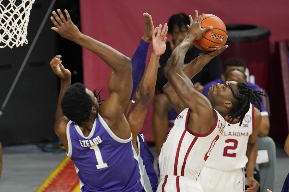 Oklahoma forward Victor Iwuakor, right, goes up for a shot while defended by Kansas State forward Kaosi Ezeagu (1) and guard Selton Miguel, center, during the first half of an NCAA college basketball game Tuesday, Jan. 19, 2021, in Norman, Okla. (AP Photo/Sue Ogrocki)