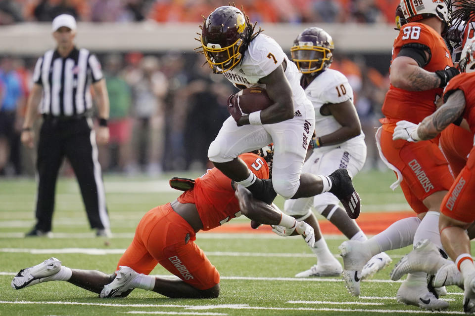 Central Michigan running back Lew Nichols III (7) is tripped by Oklahoma State safety Kendal Daniels (5) during the first half of an NCAA college football game Thursday, Sept. 1, 2022, in Stillwater, Okla. (AP Photo/Sue Ogrocki)