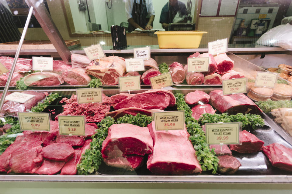 Seven butchers stand behind the counter at a family-run butcher's shop, Frampton's Butchers, Bridport, Dorset. 