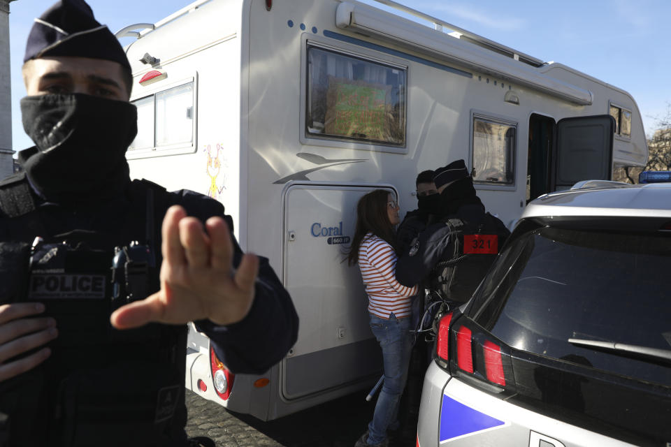 Police officers control a camper van owner on the Champs-Elysees avenue, Saturday, Feb.12, 2022 in Paris. Paris police intercepted at least 500 vehicles attempting to enter the French capital in defiance of a police order to take part in protests against virus restrictions inspired by the Canada's horn-honking "Freedom Convoy." . (AP Photo/Adrienne Surprenant)