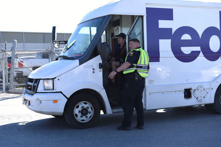 An officer with Schertz Police Department holds a FedEx truck from entering the scene of a blast at a FedEx facility in Schertz, Texas, U.S., March 20, 2018. REUTERS/Sergio Flores