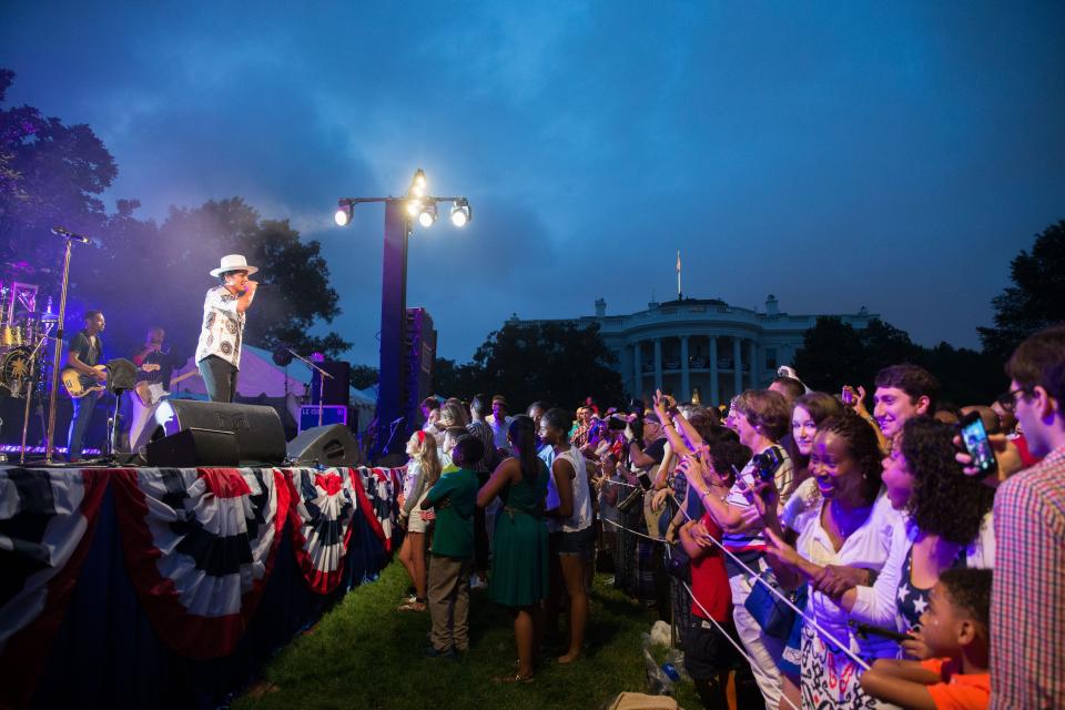 Bruno Mars, left, welcomes President Barack Obama to the stage during an Independence Day celebration on the South Lawn at the White House in Washington, Saturday, July 4, 2015.